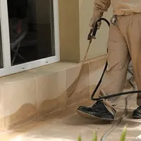 General pest control technician spraying exterior perimeter around a home in Tampa, FL